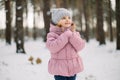Dreamy cute little girl in stylish warm winter clothes, posing outdoors in the snowy forest and looking up. Pretty child Royalty Free Stock Photo