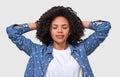 Dreamy dark-skinned young woman dressed in denim shirt and white t-shirt, holding hands on head, feel happy. African American Royalty Free Stock Photo