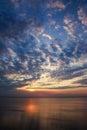 Dreamy and dramatic colorful sunset sky over water surface with cloud reflections