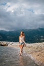 Dreamy fashion girl walk on beach with mountains background Royalty Free Stock Photo