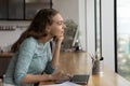 Dreamy female employee work on laptop looking in distance