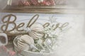 Dreamy filtered Christmas Holiday background with ornate ornaments glittery mistletoe piled in front of a sign that says believe