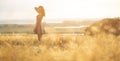 Dreamy girl in a field at sunset, a young woman in a haze from the sun enjoying nature, romantic style Royalty Free Stock Photo