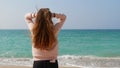 Dreamy girl with long ginger hair standing on the beach and enjoying amazing seascape, sea breeze playing with her hair Royalty Free Stock Photo