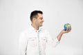 Dreamy handsome smiiling man with globe in hand thinks about which new country to visit, where to travel, isolated over Royalty Free Stock Photo