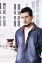 Dreamy happy well looking man drinking red wine in the kitchen