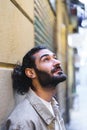 Dreamy Hispanic man leaning on wall