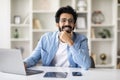 Dreamy indian freelancer man sitting at desk in home office Royalty Free Stock Photo