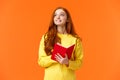 Dreamy, inspirational cute redhead female student writing daily tasks, to-do list in red lovely planner, look upper left Royalty Free Stock Photo