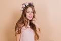 Dreamy long-haired brunette woman with purple flowers in hair smiling to camera. Interested pretty girl standing on Royalty Free Stock Photo