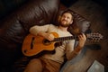 Dreamy man lying on couch playing guitar Royalty Free Stock Photo