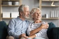 Dreamy middle aged senior retired family couple relaxing on sofa.