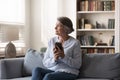 Dreamy middle aged woman holding cellphone in hands. Royalty Free Stock Photo