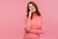 Dreamy optimistic brunette woman in pink sweater leaning head on hand imagining her perfect life, fantasizing