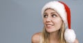 Dreamy smiling Santa girl wearing red hat looking side up. Portrait of beautiful young blue-eyed blonde woman in Royalty Free Stock Photo