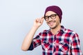 Dreamy student hipster in a casual checkered shirt, black glasses, hat, smiling and looking at the camera, standing on alight ba