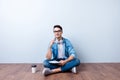 Dreamy student is sitting on the floor at home with crossed legs