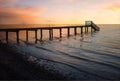 Dreamy sunset scenery at stony beach with wooden boardwalk and waves Royalty Free Stock Photo