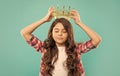 dreamy teen girl with curly hair wear crown on blue background, smug