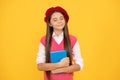 dreamy teen school girl in french beret hold copybook on yellow background, dream