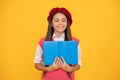 dreamy teen school girl in french beret reading book on yellow background, imagine