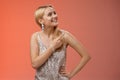 Dreamy tender attractive blond young woman in stylish silver shiny dress pointing looking upper right corner amused Royalty Free Stock Photo