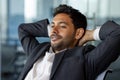 Dreamy thinking man inside office close up smiling and looking out the window, businessman in business suit with hands Royalty Free Stock Photo