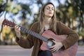 Dreamy and touched tender blonde woman, close eyes and plays guitar with pleased kind smile Royalty Free Stock Photo