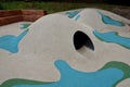 Dreamy white rubber landscape with scoops and colorful spots on the playground. stainless steel tunnel through the wave. design co