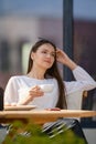 Dreamy woman sitting on the terrace of the cafe and drinking cappuccino Royalty Free Stock Photo