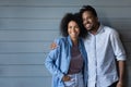 Dreamy young African American couple posing near grey wall. Royalty Free Stock Photo