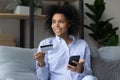 Dreamy young african female hold mobile phone and credit card