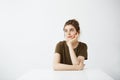 Dreamy young beautiful girl student sitting at table dreaming thinking over white background. Royalty Free Stock Photo