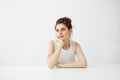 Dreamy young beautiful girl student sitting at table dreaming thinking over white background. Royalty Free Stock Photo