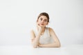 Dreamy young beautiful girl student sitting at table dreaming thinking over white background. Royalty Free Stock Photo