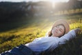 Dreamy young beautiful woman in hat lying on green grass with closed eyes enjoying summer sun spring day Royalty Free Stock Photo