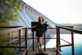 A dreamy young brunette girl stay near hydroelectric power station. Evening time. Side view Royalty Free Stock Photo