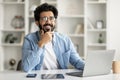 Dreamy Young Indian Man Sitting At Desk With Laptop In Home Office Royalty Free Stock Photo