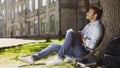 Dreamy young male sitting with notebook under tree, thinking what to write, idea