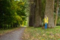 Dreamy young woman is leaning on trunk of large old tree in park Royalty Free Stock Photo