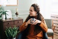 Dreamy young woman savoring warm coffee in cozy home interior. Beautiful lady enjoying a hot drink while relaxing at home. Serene Royalty Free Stock Photo