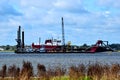 Dredging barge being secured by tugboats