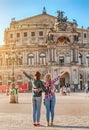 Two happy Women friends hugging and admiring view of Semper Opera Theatre in Dresden