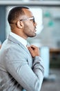 Dress the part. a young businessman adjusting his tie in an office. Royalty Free Stock Photo