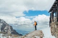 Dressed bright orange jacket backpacker walking in High Tatras mountain range, Slovakia using trekking poles. Hiker standing near Royalty Free Stock Photo