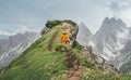 Dressed bright orange softshell jacket runner running by green mountain path with picturesque Dolomite Alps range background,. Royalty Free Stock Photo