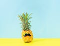 Dressed cheerful pineapple with mustache a blue yellow background. Creative concept of summer vacation . Glitch effect.
