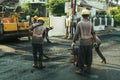 Dressed in street workers' uniforms, workers repair a road in Ciledug, near Jakarta, Indonesia