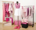 Dressing closet with pink clothes arranged on hangers and an outfit on a mannequin.