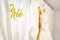 Dressing gown with golden bride inscription hanging on the wall with a wedding dress Royalty Free Stock Photo